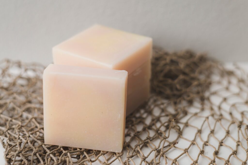 Handcrafted bar soap on a natural fiber mesh background.